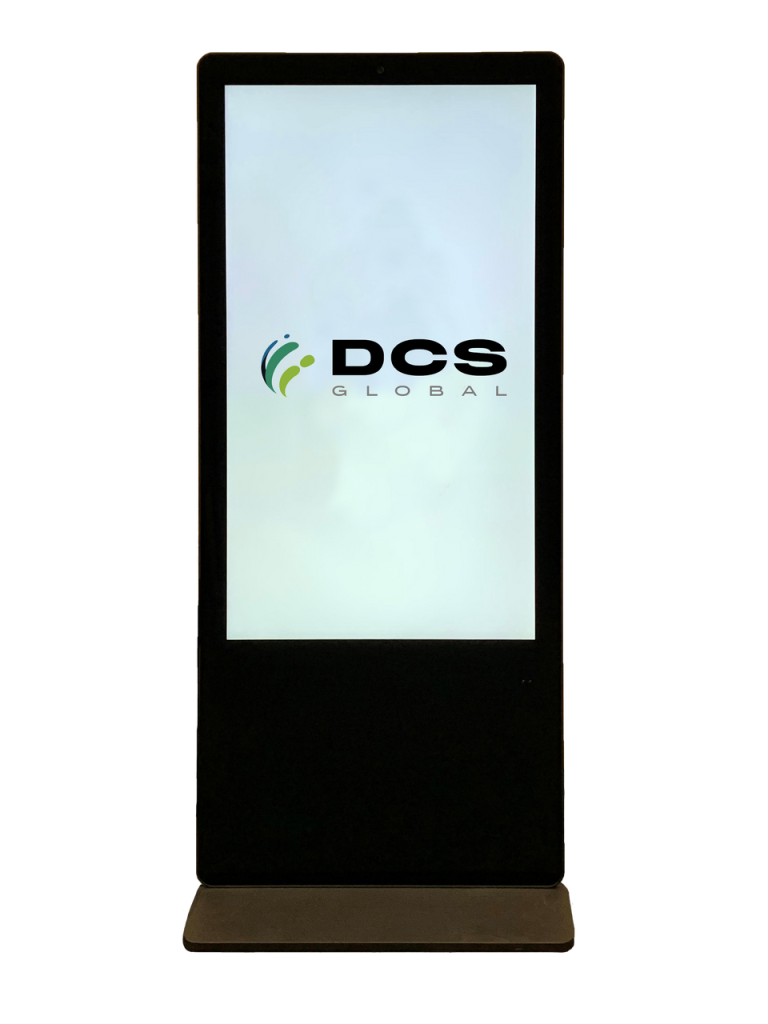 A black kiosk stands upright with a bright touchscreen displaying the logo of DCS Global. The logo consists of the text "DCS Global" accompanied by a green and grey abstract design on the left side.