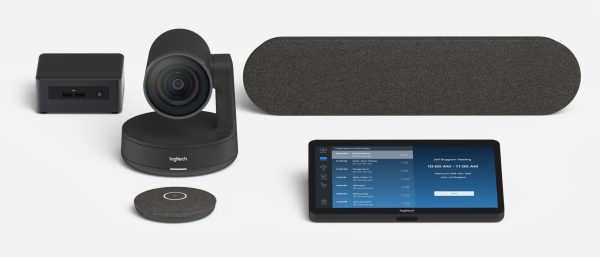 A setup of Logitech Room Solutions for Zoom Rooms - Medium on a white surface. The arrangement features a camera, a speaker, a control tablet displaying a meeting interface, a microphone, and a hub. The devices are primarily black with sleek, modern designs.