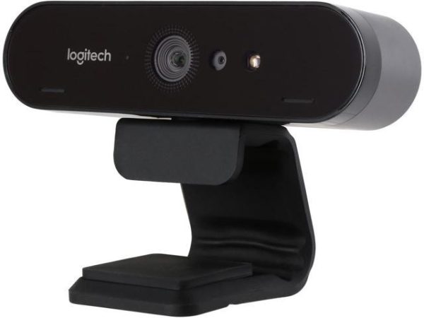 A Logitech Brio webcam with a sleek black design is mounted on a flexible stand. The camera lens is positioned slightly off-center, with a built-in microphone and LED indicator visible next to it. The Logitech logo is displayed on the top left corner of the device.