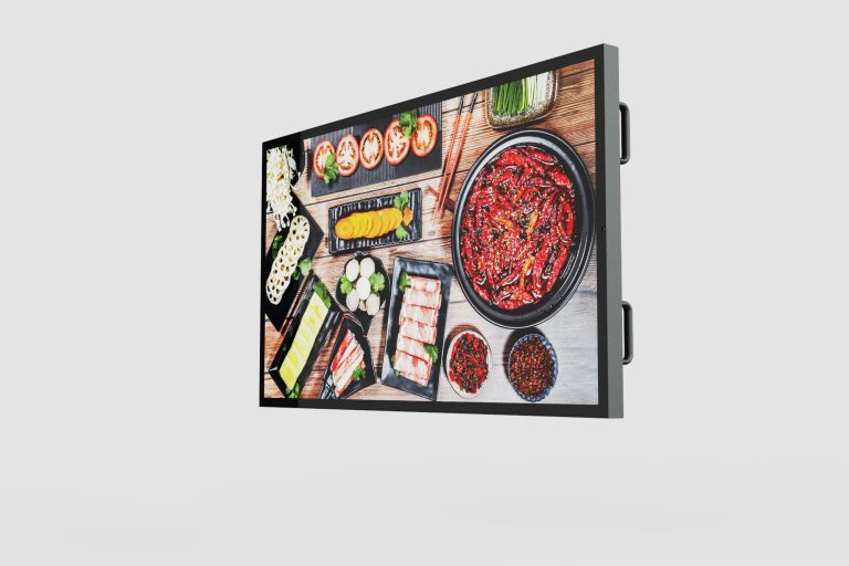 A digital display showcases a variety of colorful dishes, including a large bowl of red chili peppers. The surrounding table is filled with plates of sliced vegetables, sushi rolls, and various condiments, all presented on a light wooden background.